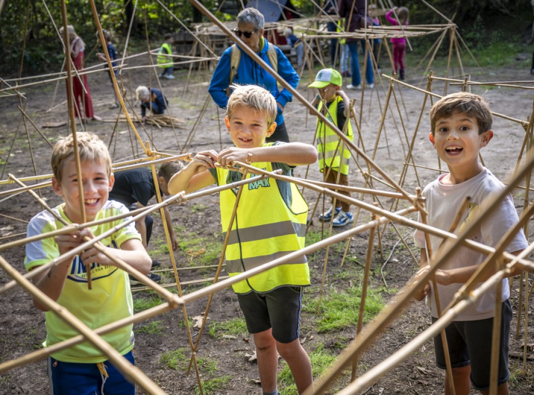 Drie MikMakkers die bamboo stokken aan elkaar knopen