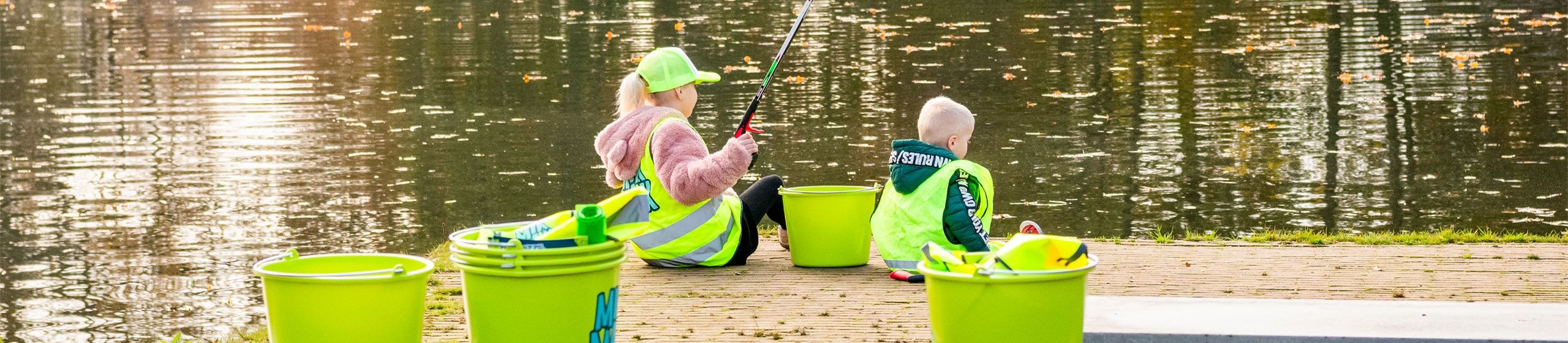 twee MikMakkers op de kant van de vijver aan het plastic vissen