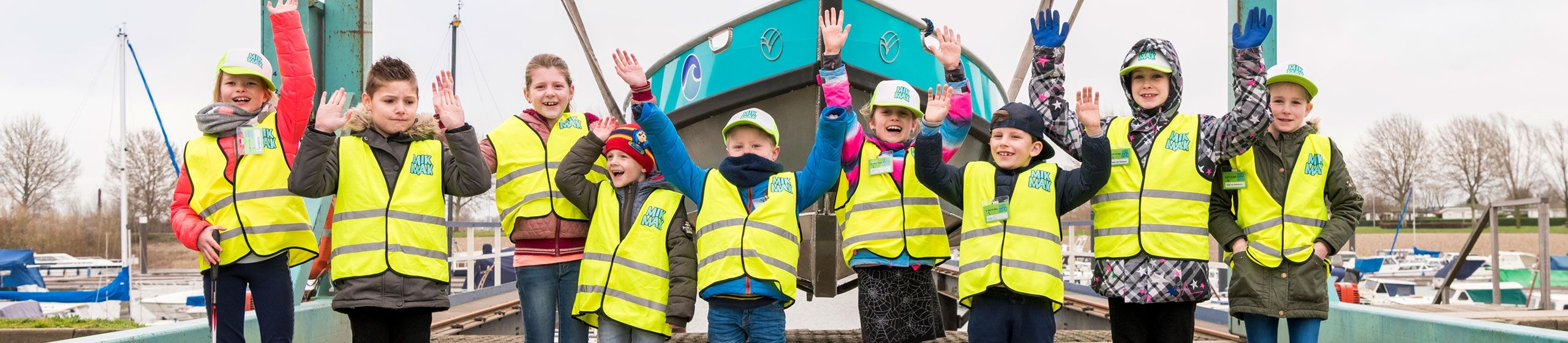 9 MikMakkers juichend op een rijtje voor een schip